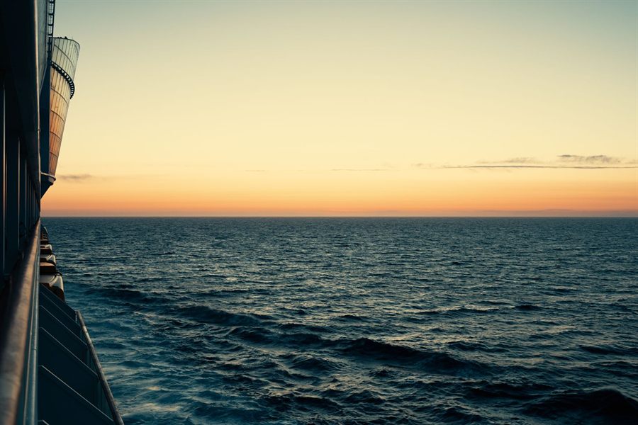 Golden sunset over the open ocean seen from the side of a cruise ship