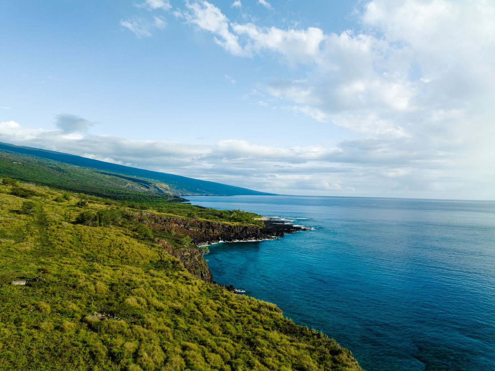 Green slopes meeting deep blue water along the Kona coast of the Big Island